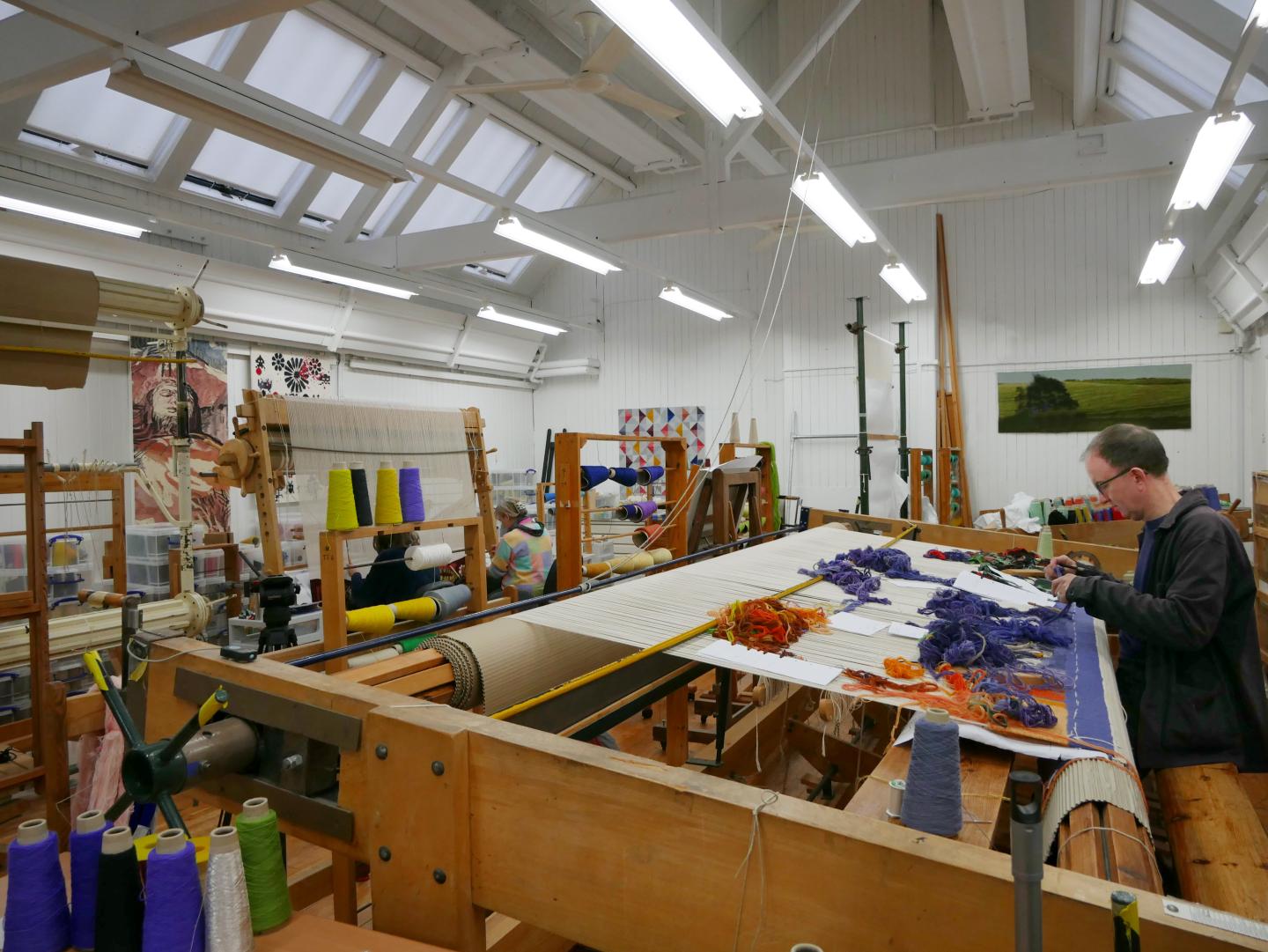 A tapestry weaver at work on a loom in a studio